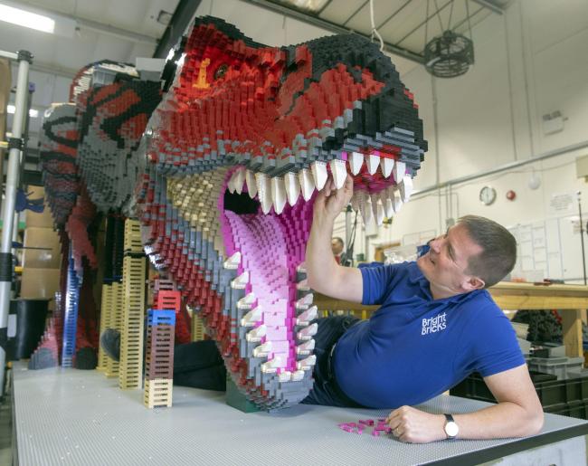 Bright Bricks member of staff Ed Diment works on a life-size T-Rex made out of LEGO during a press preview of Marwell Zoo's new Lego Brickosaurs at Bright Bricks HQ in Bordon, Hampshire. PRESS ASSOCIATION Photo. Picture date: Wednesday February 13,