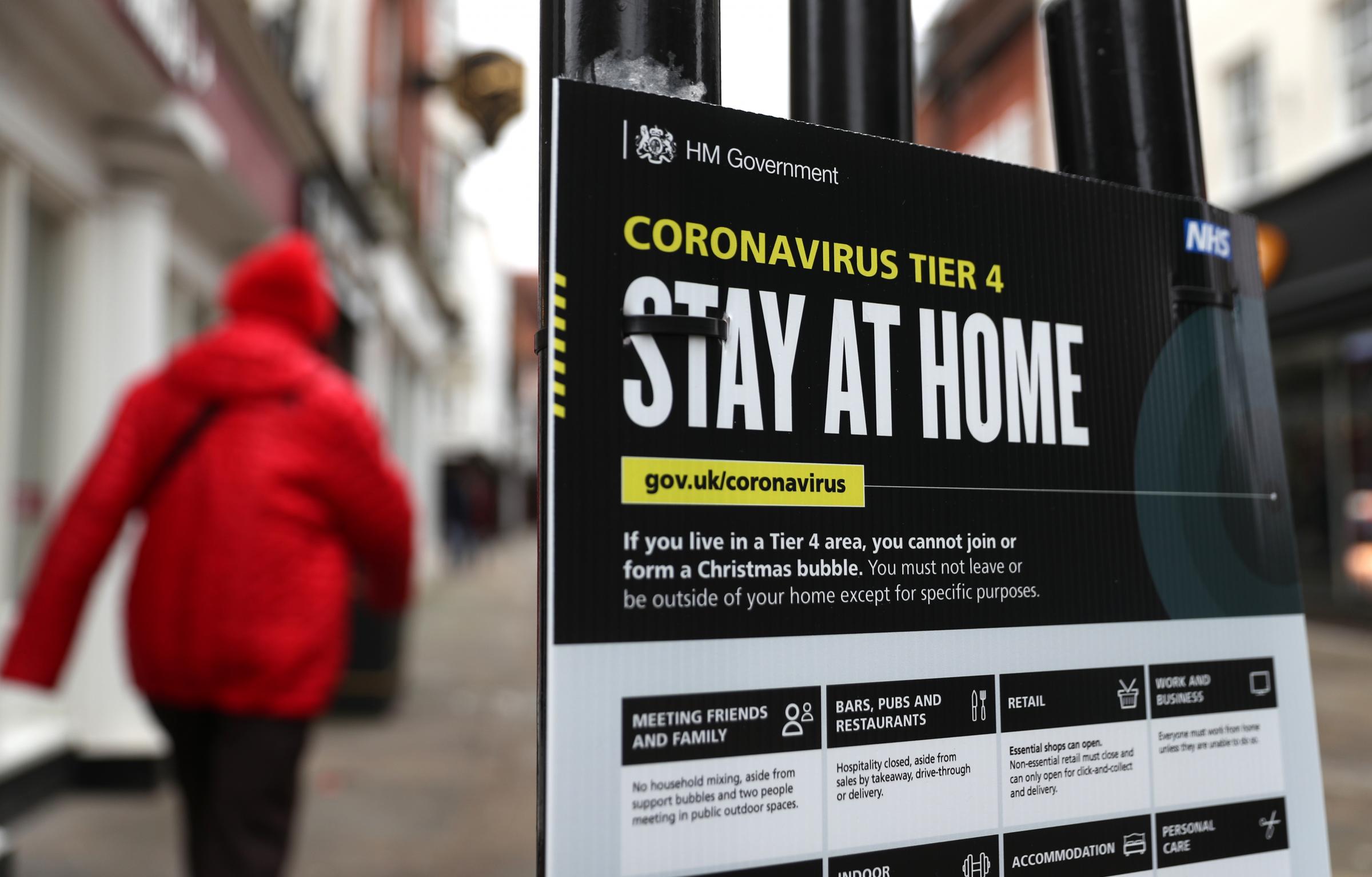 People make their way past a Government coronavirus Tier 4 sign on the High street in <a href=