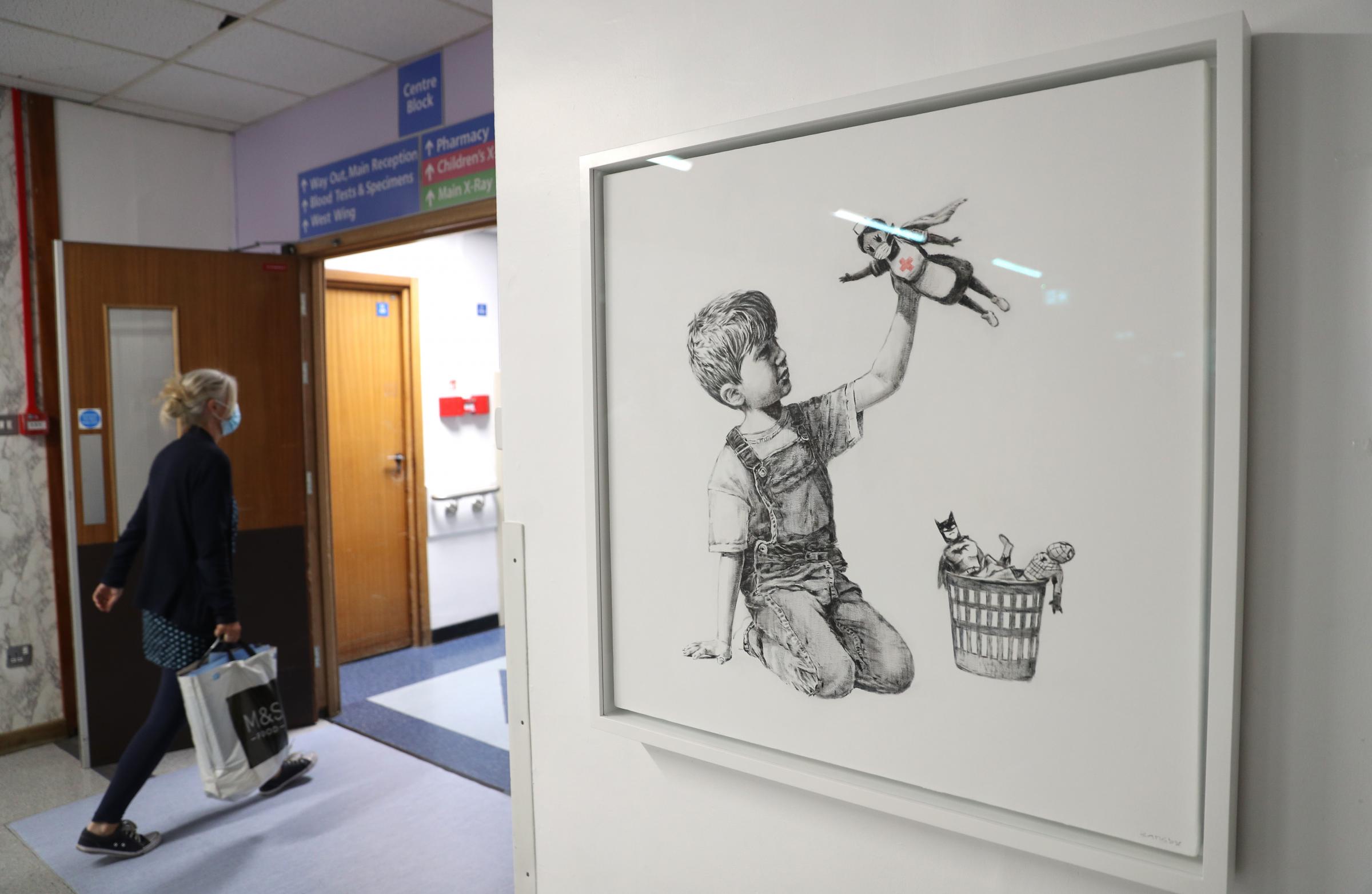 File photo dated 7/5/2020 of person walks past the new artwork painted by Banksy during lockdown, entitled Game Changer, which has gone on display to staff and patients on Level C of Southampton General Hospital. Banksy is hoping to raise more than