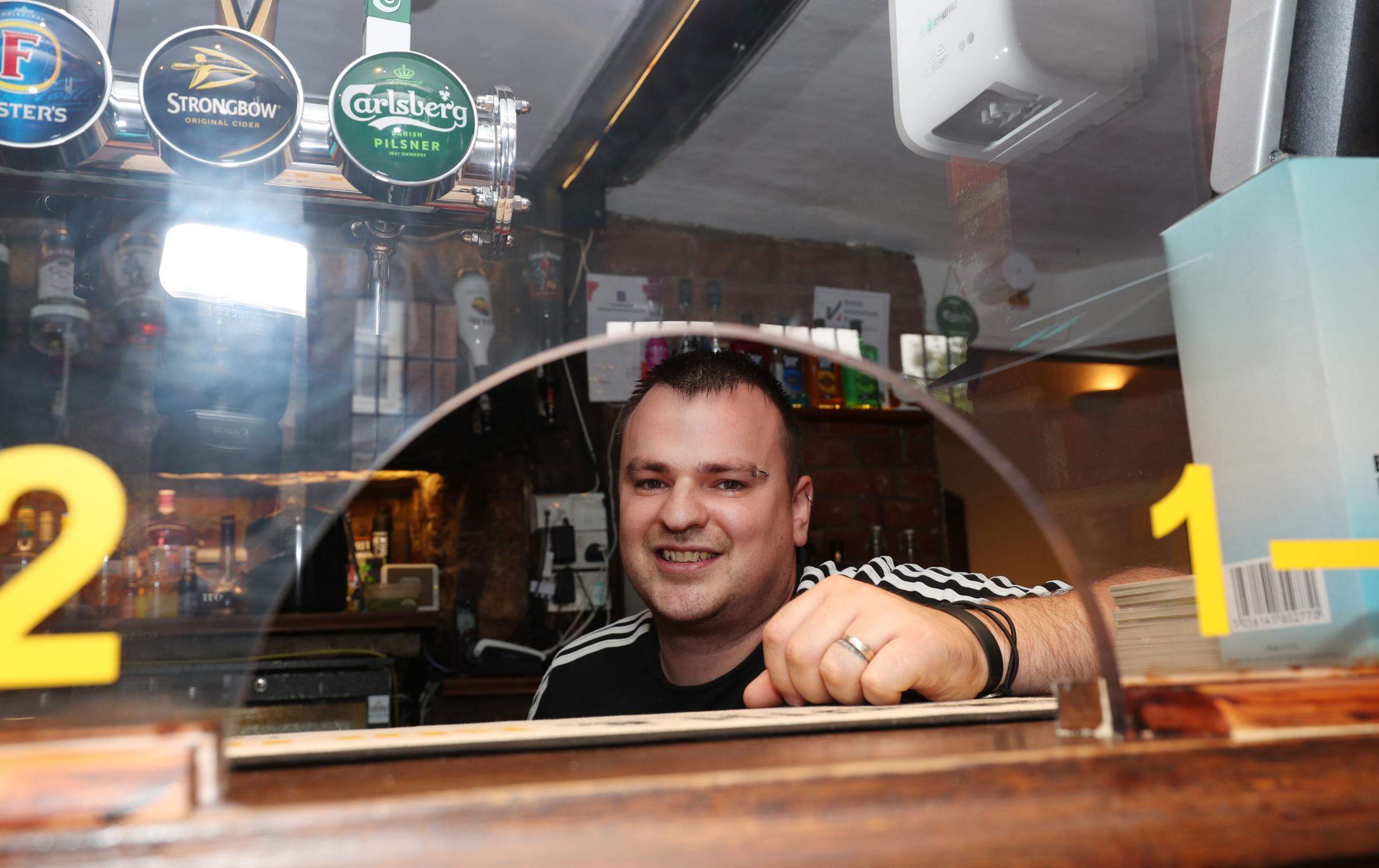 Pub and cafes reopen in Winchester after coronavirus restrictions were relaxed on Saturday 4th July. Rob Plunton behind the bar of the Rising Sun pub..