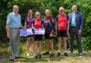 Former Club Chair John Spiers and current Chair Sue Coles display the award certificates from Cycling UK with four riders who cycled with the Club in 1983 – Martine Hebblethwaite (née Wilson), Simon Green, Stephen Harrison and Richard Wicks