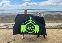 Mark Ryan and Peter Brown hold up the Winnall Rock School banner at Lepe Beach