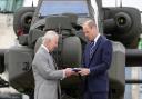 King Charles III officially hands over the role of Colonel-in-Chief of the Army Air Corps to the Prince of Wales, in front of an Apache helicopter, during a visit to the Army Aviation Centre at Middle Wallop, near Andover