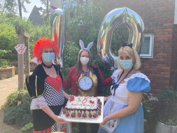 Hampshire Chronicle: With the St Catherines View tenth anniversary cake are, from left: Home Manager and Queen of Hearts Vanda Baker, Companionship Team Leader and White Rabbit Laura Sheldrake; and Clinical Lead, and Alice herself, Hayley Geddes.