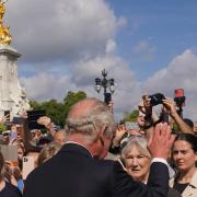 King Charles III is greeted by well-wishers during a walkabout to view tributes left outside Buckingham Palace.