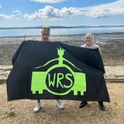 Mark Ryan and Peter Brown hold up the Winnall Rock School banner at Lepe Beach