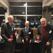 The principal speakers at the launch: Professor Martin Biddle (right) and Dr Francis Morris (centre), each holding one part of the newly published Venta Belgarum and Dr Giles Clarke (left), with The Roman cemetery at Lankhills. Photo: T.Maloney
