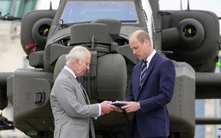 King Charles III officially hands over the role of Colonel-in-Chief of the Army Air Corps to the Prince of Wales, in front of an Apache helicopter, during a visit to the Army Aviation Centre at Middle Wallop, near Andover
